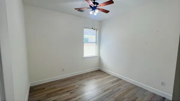 an empty room with a window and wooden floor