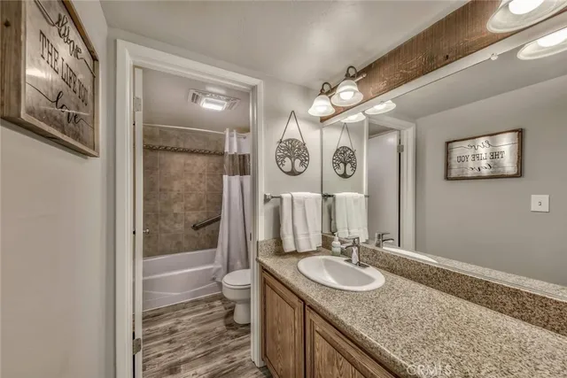a bathroom with a granite countertop sink a toilet a mirror and shower