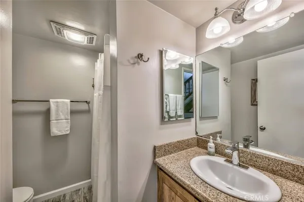 a bathroom with a granite countertop sink a light fixture and a mirror