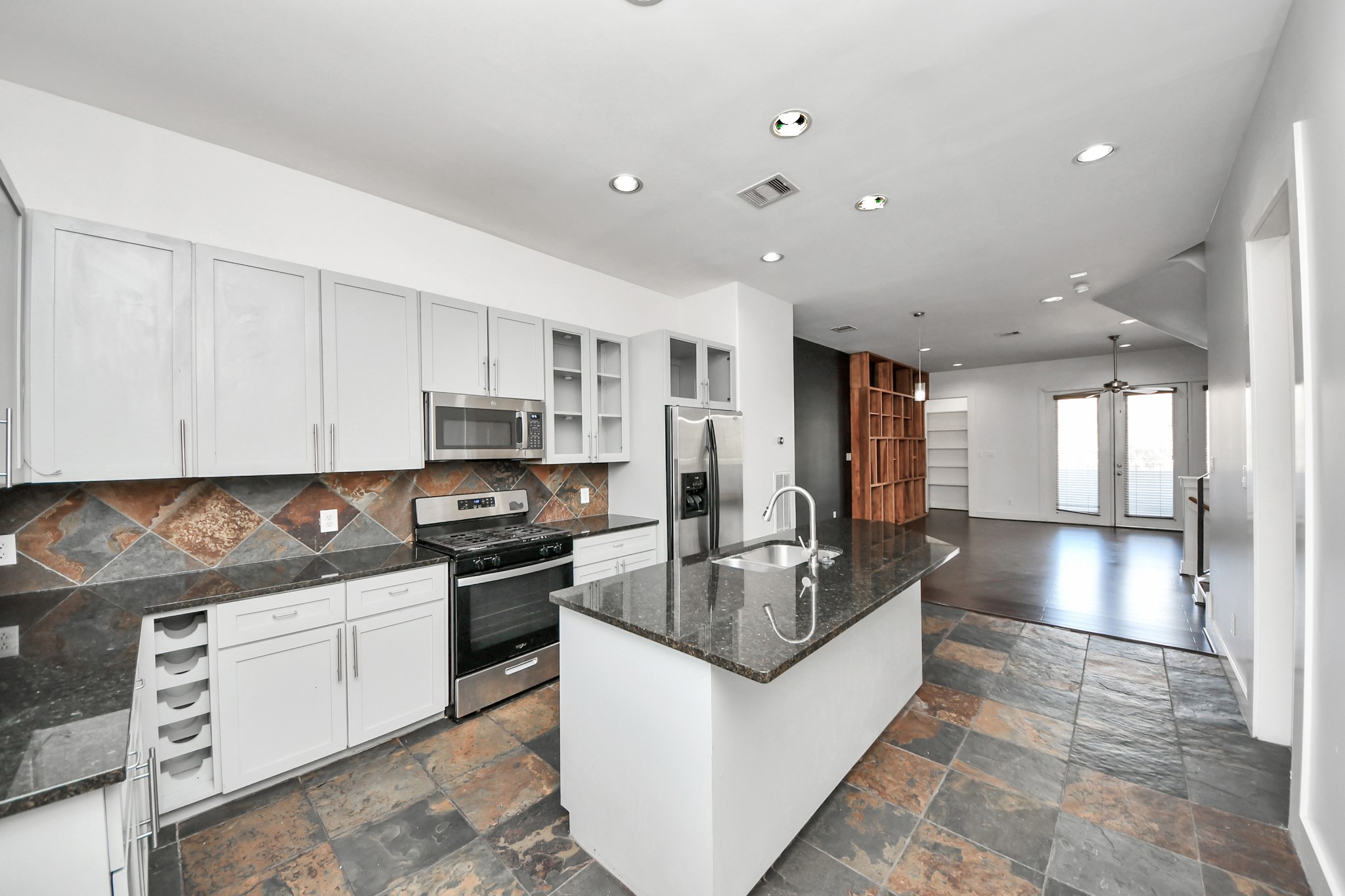 a kitchen with stainless steel appliances granite countertop a sink a stove and a refrigerator