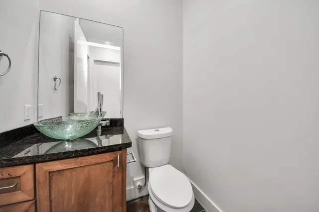 a bathroom with a granite countertop sink and a toilet