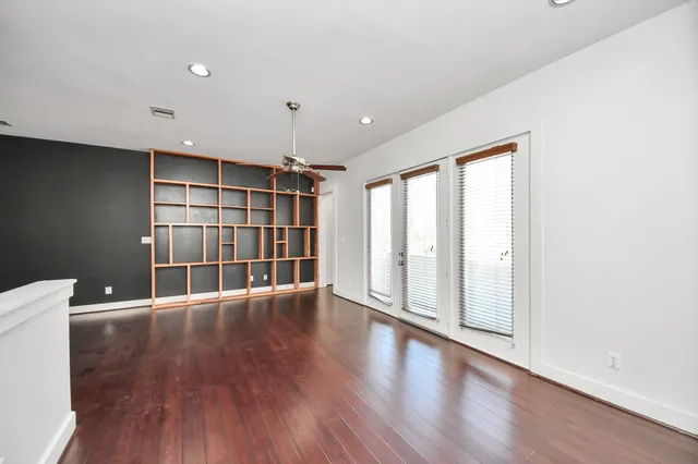 a view of an empty room with wooden floor and staircase
