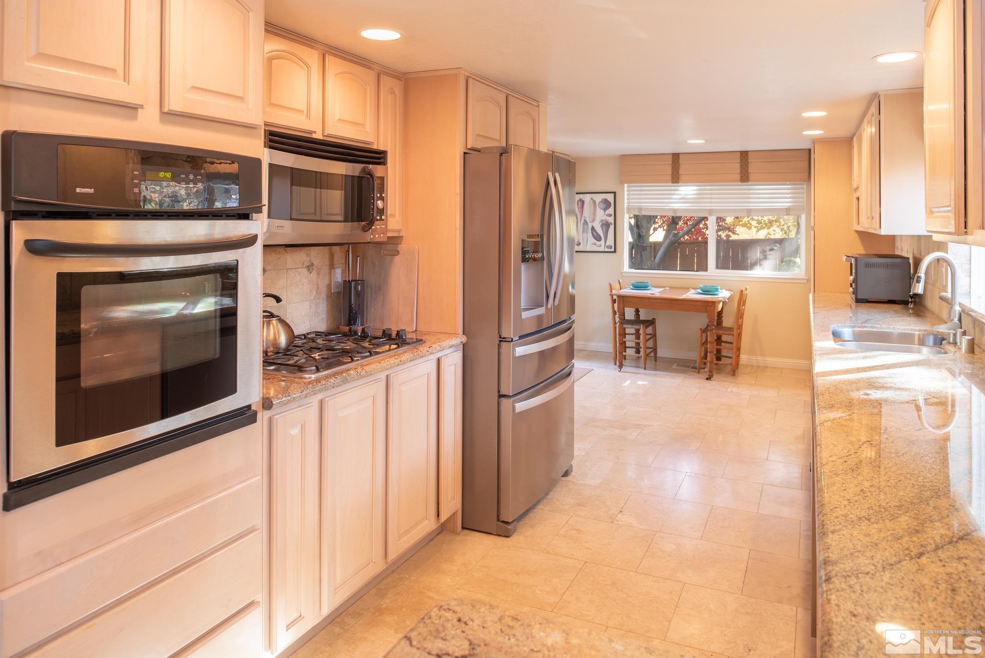 6328 Windy Meadow Drive Reno, NV 89519 - Photo 8 of 35 a kitchen with stainless steel appliances kitchen island granite countertop a refrigerator and a stove top oven