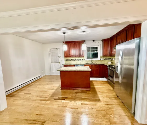 a kitchen with granite countertop a refrigerator and a stove top oven