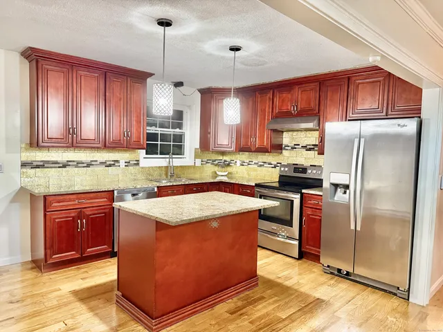a kitchen with stainless steel appliances granite countertop a stove refrigerator sink and cabinets