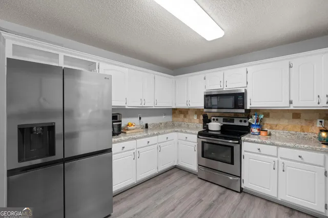 a kitchen with cabinets stainless steel appliances and wooden floor