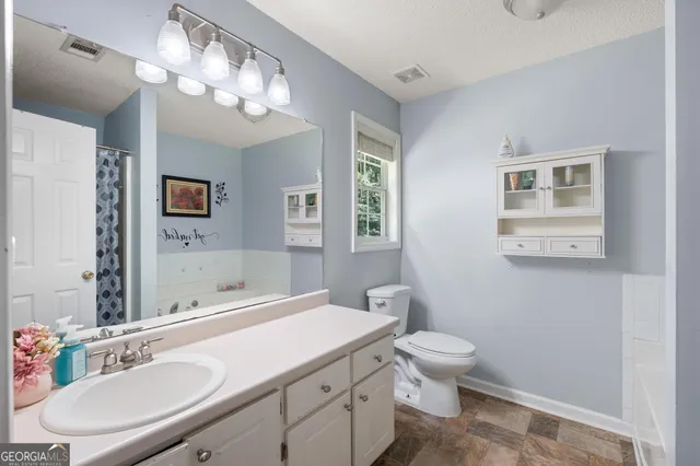 a bathroom with a toilet a sink a mirror a window and vanity