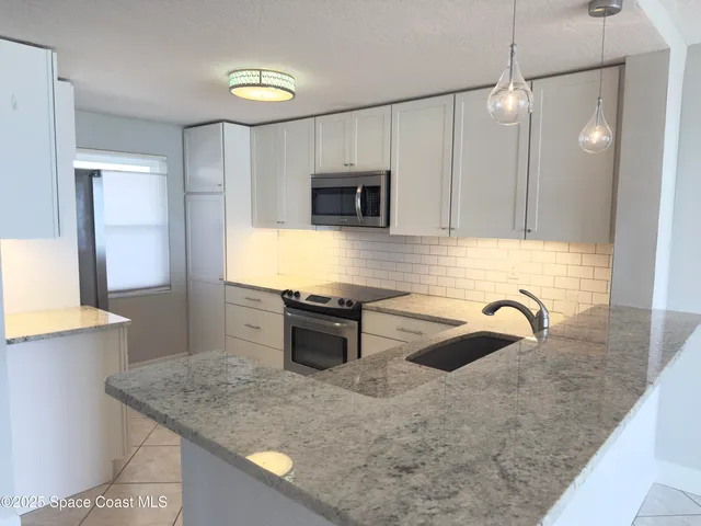 a kitchen with stainless steel appliances granite countertop a sink a microwave a stove and a refrigerator