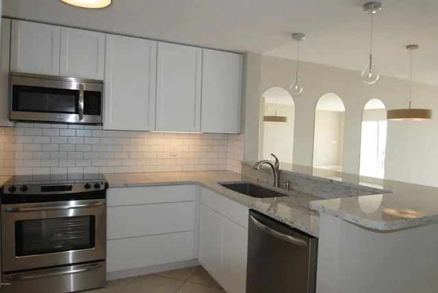 a kitchen with stainless steel appliances granite countertop a sink a stove and microwave