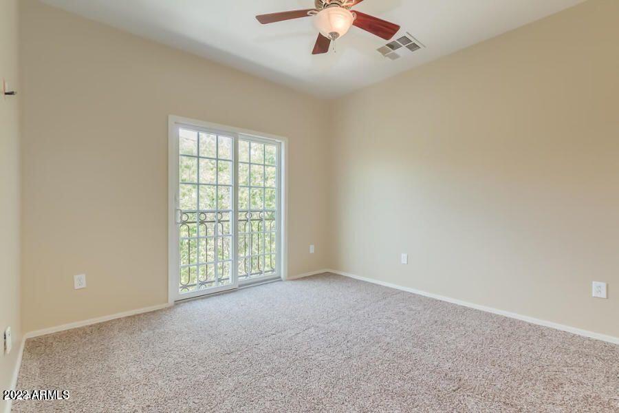 4750 East Thunderheart Trail, Unit 102 Gilbert, AZ 85297 - Photo 15 of 25 an empty room with chandelier fan and windows
