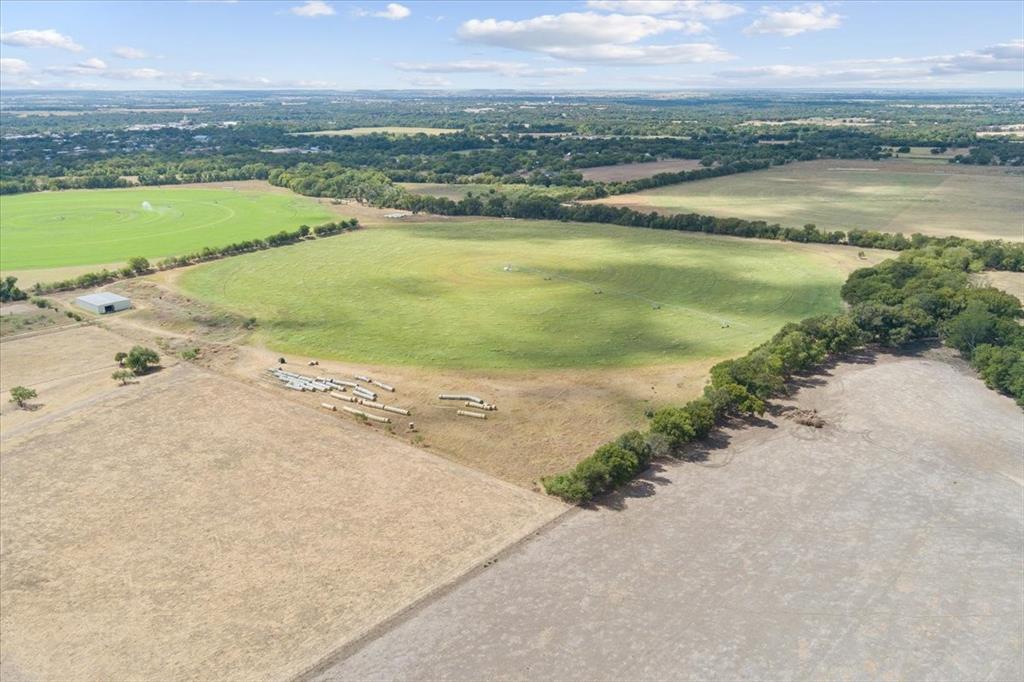 410 State School Road Gatesville, TX 76528 - Photo 12 of 39 Expansive agricultural land featuring a large green field, additional cultivated fields, a metal utility building, and a distant treeline
