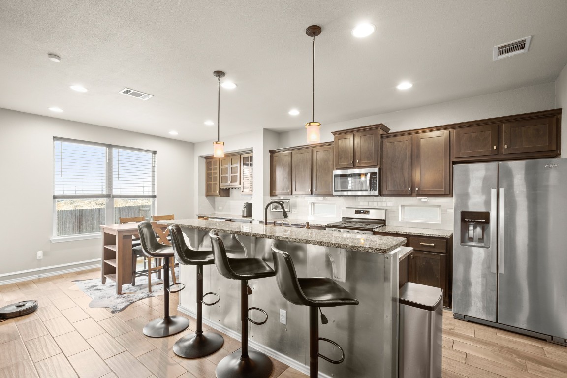 1006 Chad Loop Round Rock, TX 78665 - Photo 3 of 26 a kitchen with stainless steel appliances granite countertop a stove top oven a refrigerator a sink and chairs