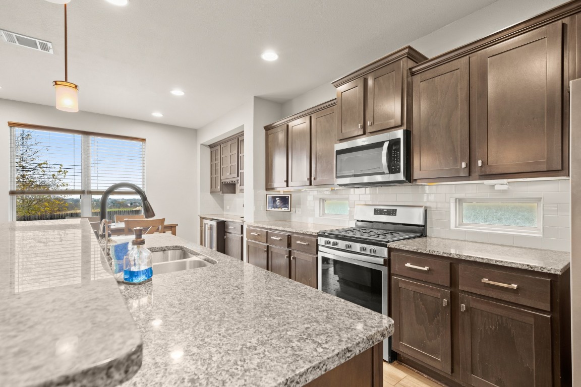 1006 Chad Loop Round Rock, TX 78665 - Photo 4 of 26 a kitchen with stainless steel appliances granite countertop a sink stove microwave and refrigerator