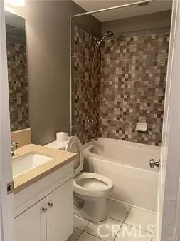 a bathroom with a granite countertop bathtub shower sink vanity and toilet