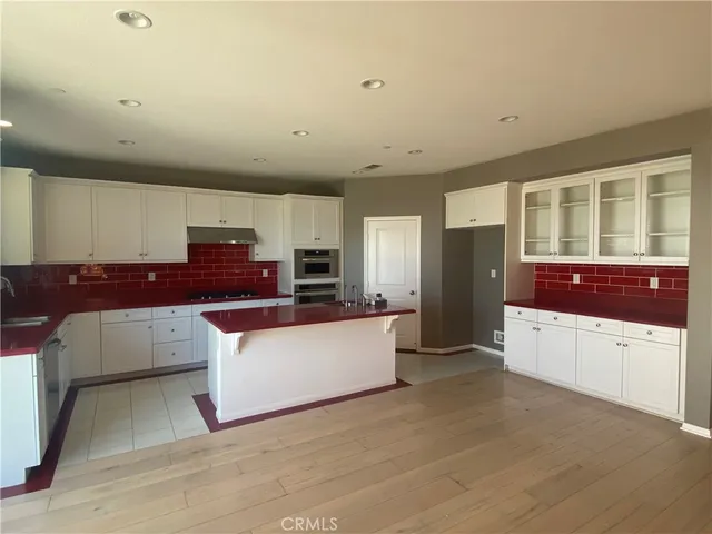 a large white kitchen with stainless steel appliances granite countertop a stove and a refrigerator