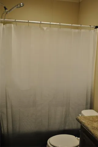 a bathroom with a granite countertop toilet and a shower