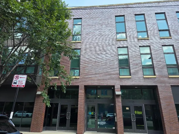 a front view of a building with glass windows and a tree