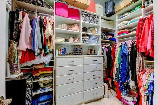 a view of walk in closet with clothes and shoes