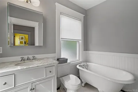 a bathroom with a toilet a sink a tub and mirror