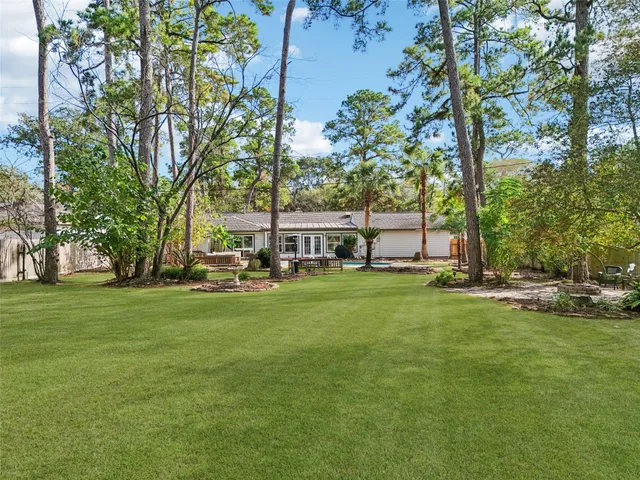 a view of a house with a big yard and large trees