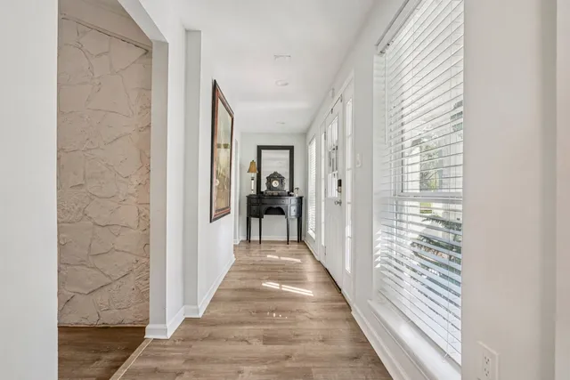 a view of a hallway with wooden floor and windows