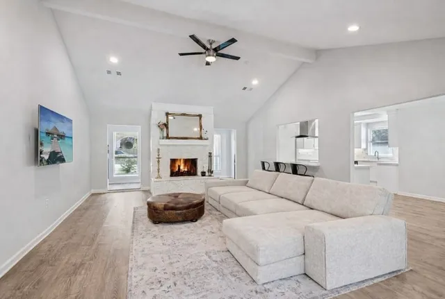 a living room with furniture a fireplace and a ceiling fan