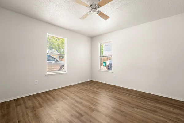 a view of an empty room with a window and wooden floor