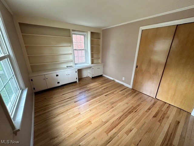15959 Glynn Road Cleveland, OH 44112 - Photo 20 of 23 Unfurnished bedroom with built in desk, light wood-type flooring, ornamental molding, and a closet