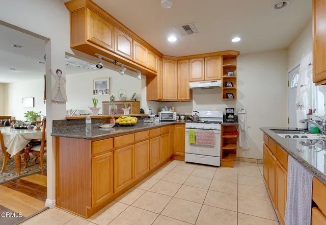 a kitchen with granite countertop a stove top oven sink and cabinets