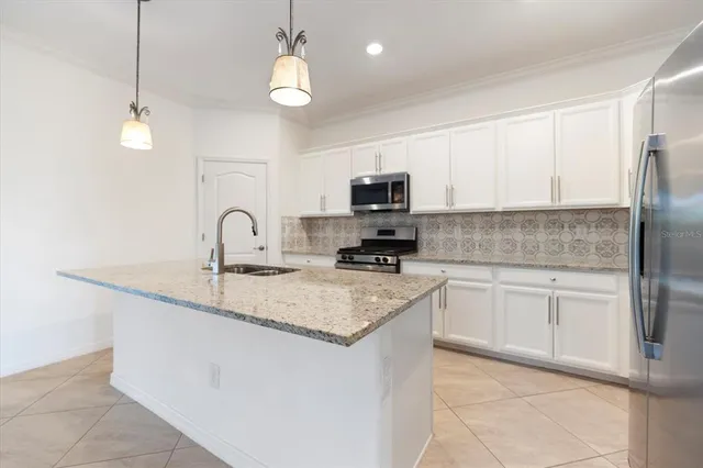 a kitchen with granite countertop a sink a counter top space and cabinets
