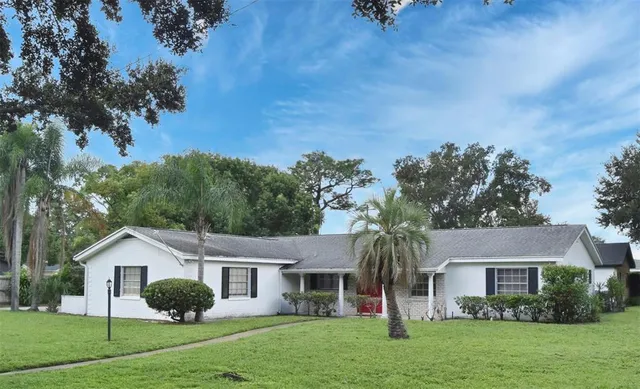 a front view of a house with a garden and trees