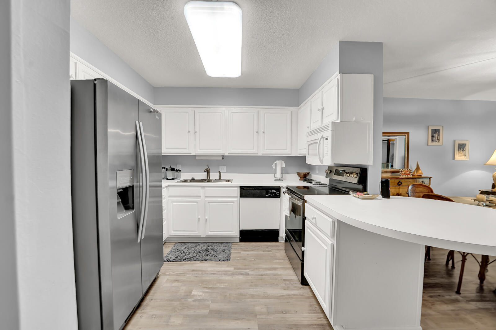 30 Moreno Point Road, Unit 102A Destin, FL 32541 - Photo 24 of 52 a kitchen with a refrigerator a sink and dishwasher with white cabinets