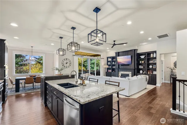a kitchen with stainless steel appliances granite countertop a sink a stove and a wooden floors