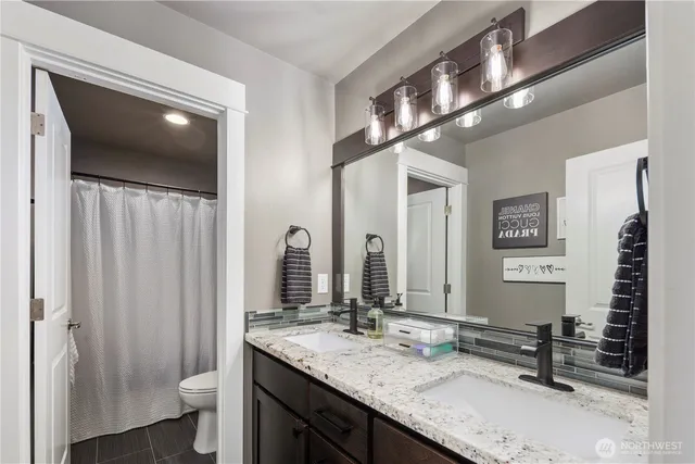a bathroom with a granite countertop sink a toilet and a mirror