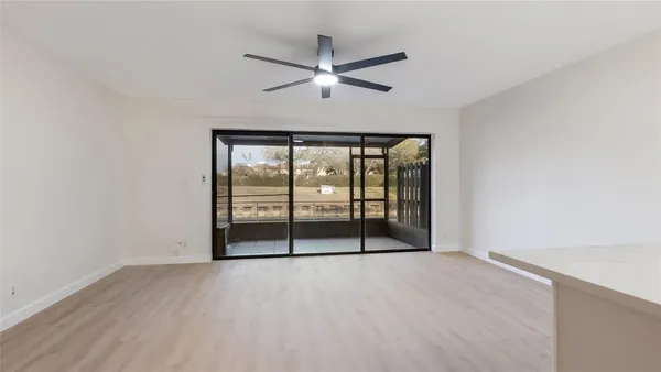 an empty room with wooden floor and fan