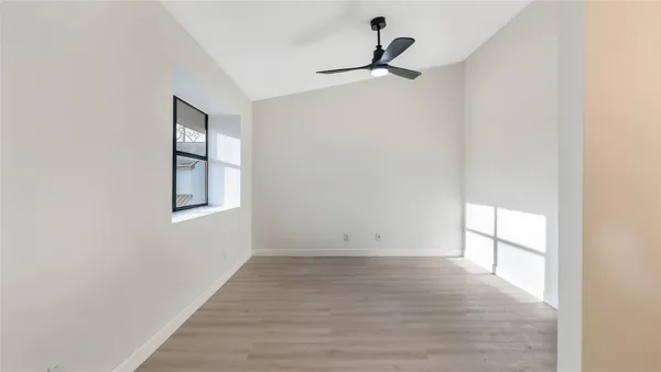 a view of empty room with wooden floor and fan