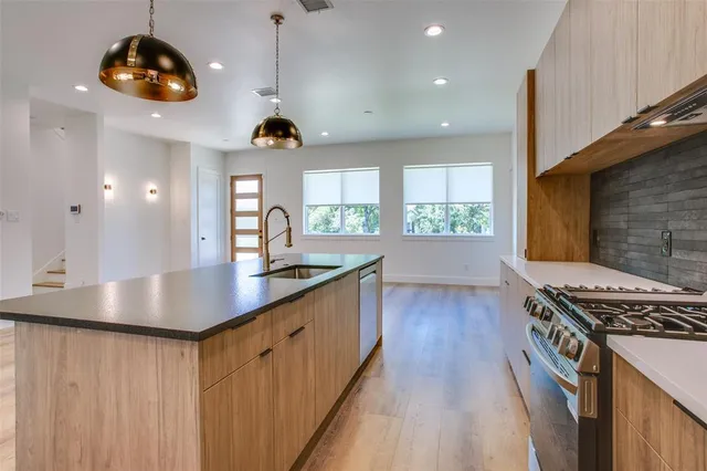 a kitchen with stainless steel appliances a stove a sink a counter space and a window