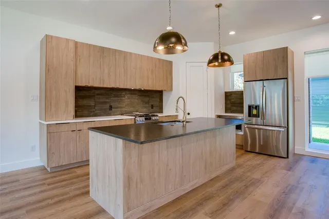 a kitchen with stainless steel appliances granite countertop a sink a stove and a refrigerator