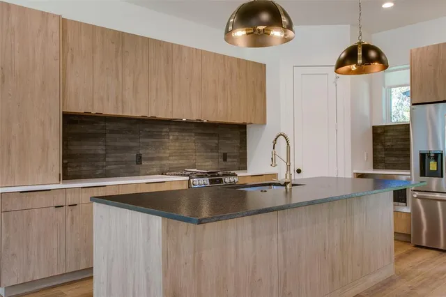 a kitchen with stainless steel appliances a sink a stove and a wooden floors