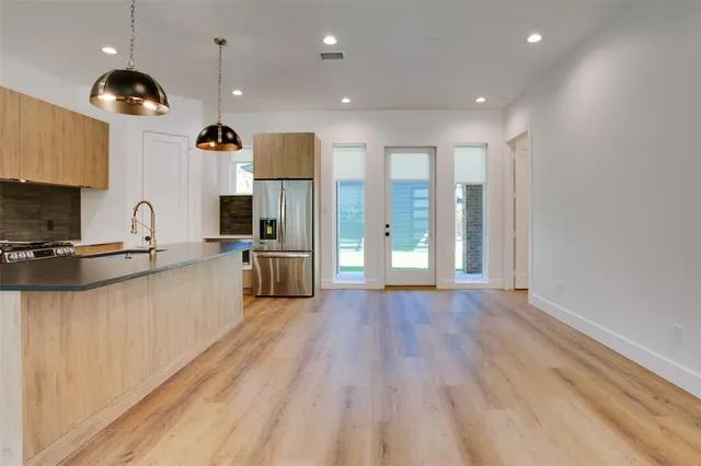 a large kitchen with stainless steel appliances kitchen island a large counter top and wooden floors