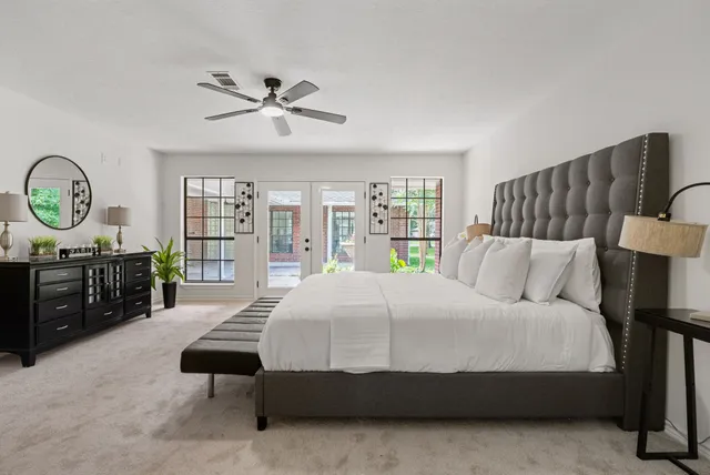 a bedroom with a bed a dresser and a large window