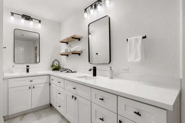 a bathroom with a double vanity sink mirror and bathtub