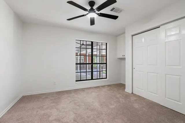 an empty room with windows and ceiling fan