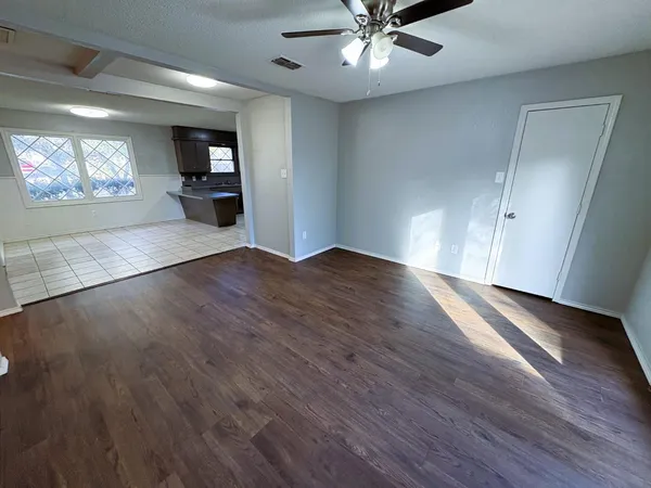 a view of an empty room with window and wooden floor