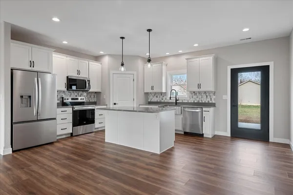 a kitchen with a refrigerator a sink and a stove top oven