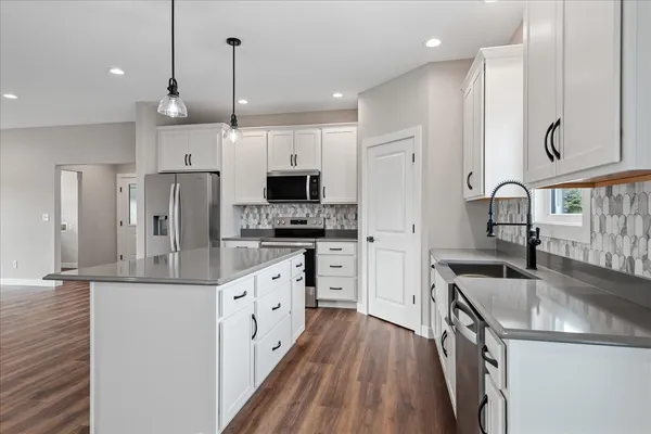 a kitchen with stainless steel appliances kitchen island granite countertop a sink stove a refrigerator a oven with a dining table and chairs