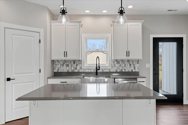 a kitchen with kitchen island granite countertop a sink a counter top space and stainless steel appliances
