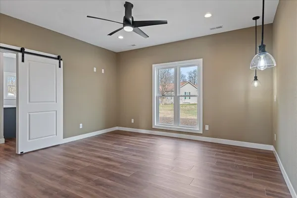 a view of an empty room with a window and wooden floor