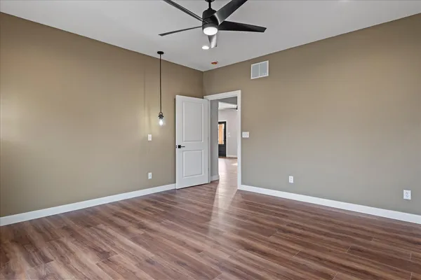 a view of an empty room with window and wooden floor