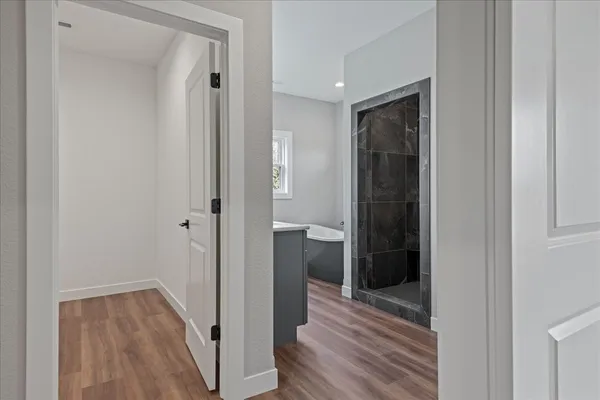 a view of a hallway with wooden floor and closet